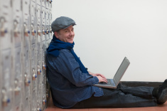 stock-photo-26601750-mature-student-leaning-against-lockers-with-laptop